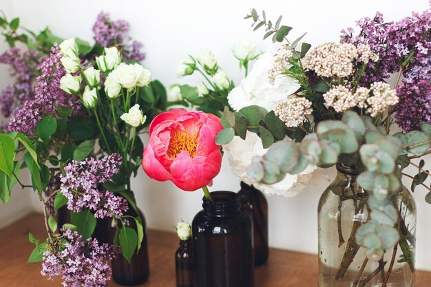 Fleurs modernes nature morte belles pivoines roses lilas fleurs d'hortensias dans des bouteilles en verre