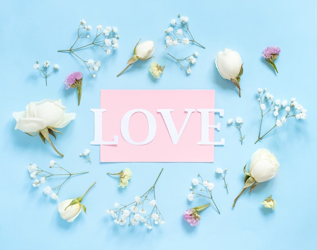 Fleurs et mot LOVE sur une vue de dessus de fond bleu clair