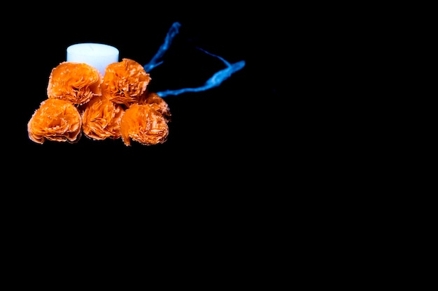 Photo des fleurs de papier orange avec une bougie sur fond noir pour halloween ou le jour des morts