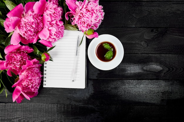 Fleurs de pivoine sur fond noir avec une note ou un journal intime