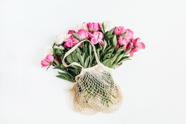 Fleurs de pivoine rose et blanc dans un sac à cordes sur une surface blanche