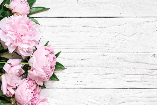 Fleurs de pivoine rose sur une table en bois blanche avec espace copie. invitation de mariage. mise à plat