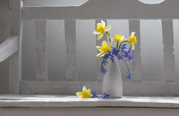 Fleurs de printemps dans un vase sur un banc en bois blanc