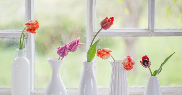 Fleurs de printemps dans un vase blanc sur le vieux rebord de la fenêtre