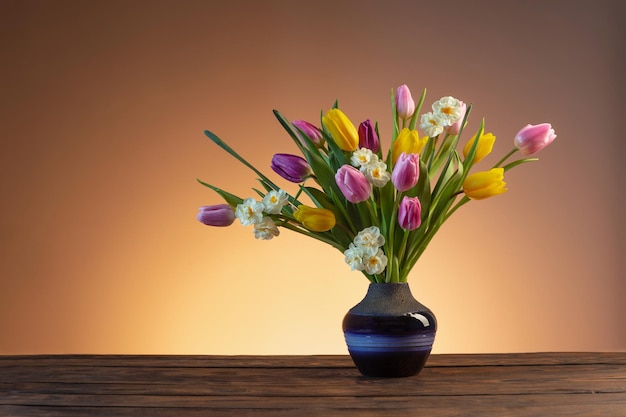 Fleurs de printemps dans un vase en céramique bleu sur une table en bois