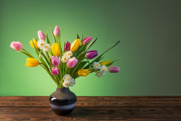 Fleurs de printemps dans un vase en céramique bleu sur une table en bois