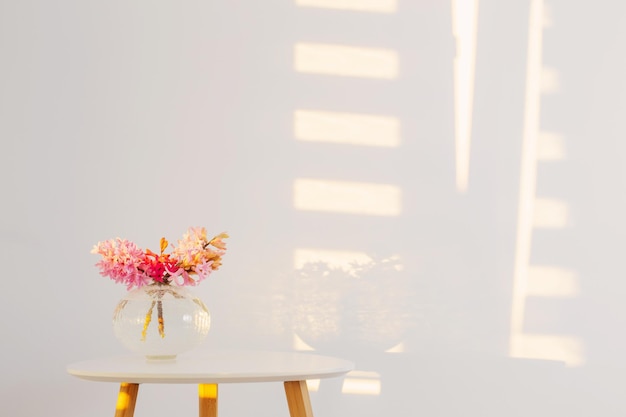 Fleurs de printemps dans un vase en verre sur fond mur blanc au soleil