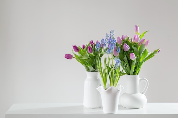 Photo fleurs de printemps dans des vases blancs dans un intérieur blanc