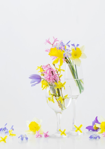 Fleurs de printemps en verre à vin sur une surface blanche