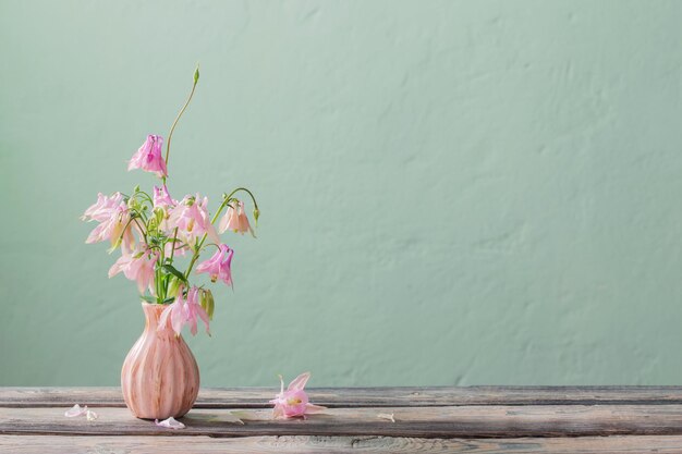 Fleurs roses dans un vase rose sur fond de mur vert