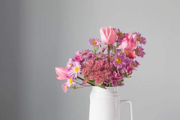 Fleurs roses en pot blanc sur fond gris mur