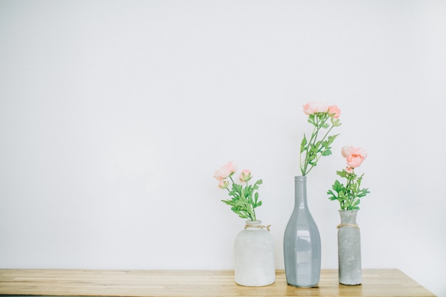 Fleurs roses rose pastel dans des vases près du blanc.