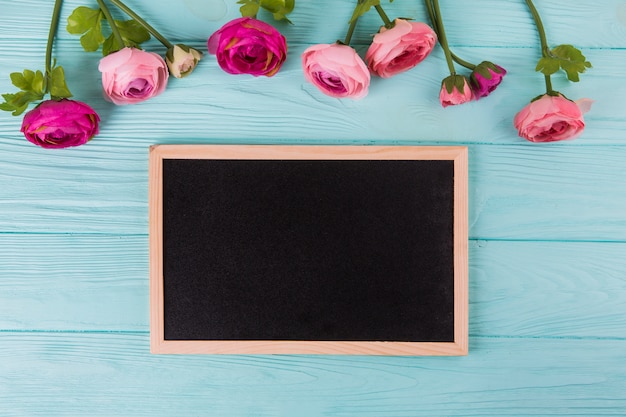 Fleurs roses roses avec tableau sur table en bois