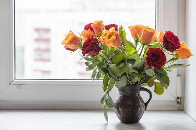 Fleurs roses rouges et jaunes en pot sur le rebord de la fenêtre