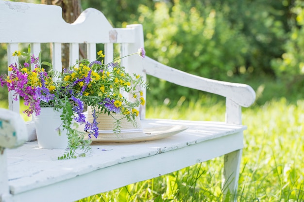 Fleurs sauvages sur un banc en bois blanc dans le jardin d'été