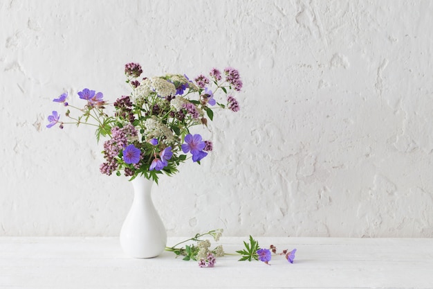 Fleurs sauvages dans un vase blanc sur fond blanc