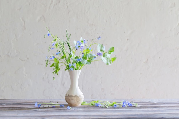 Fleurs sauvages dans un vase sur fond blanc vieux mur