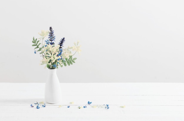 Fleurs sauvages dans un vase sur fond blanc