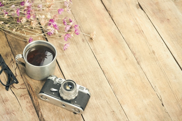 Fleurs sauvages, tasse de thé en métal, boussole et autres attributs pour une randonnée sur une surface en bois. Concept de randonnée en montagne ou en forêt, tourisme, repos de tente, camp. Mise à plat, vue de dessus.