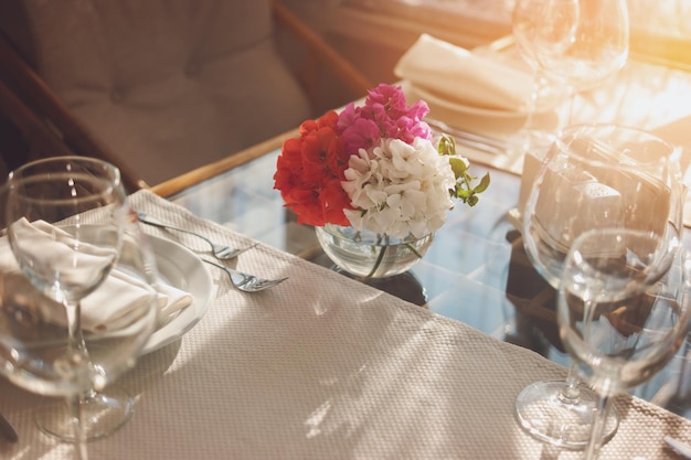 Des fleurs sur une table à manger, des verres à vin vides et une assiette invitent vos voisins à prendre le petit-déjeuner