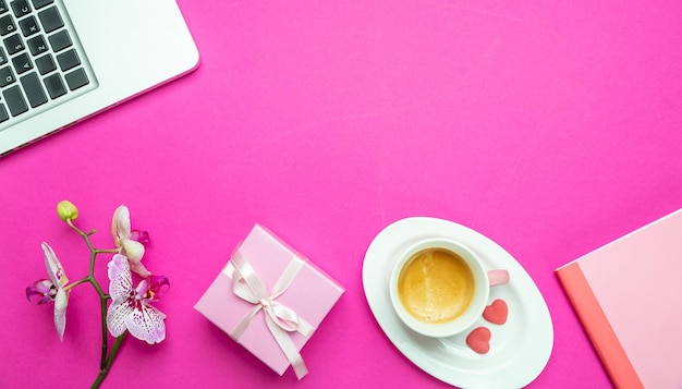 Fleurs tasse de café et ordinateur portable sur l'espace de copie de fond de bureau rose