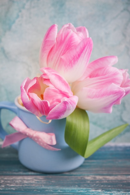 Fleurs de tulipe rose dans une tasse bleue