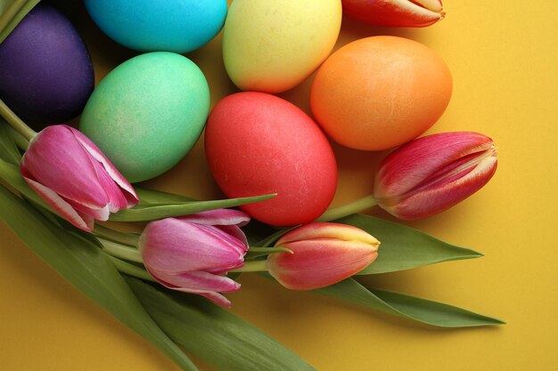 Fleurs de tulipes colorées fraîches et oeufs de pâques sur fond jaune Vue de dessus avec espace de copie Carte de voeux joyeuses pâques