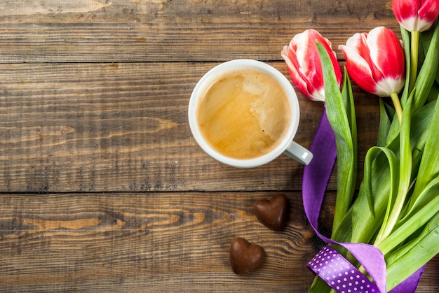 Fleurs de tulipes fraîches de printemps avec des bonbons au chocolat et une tasse de café