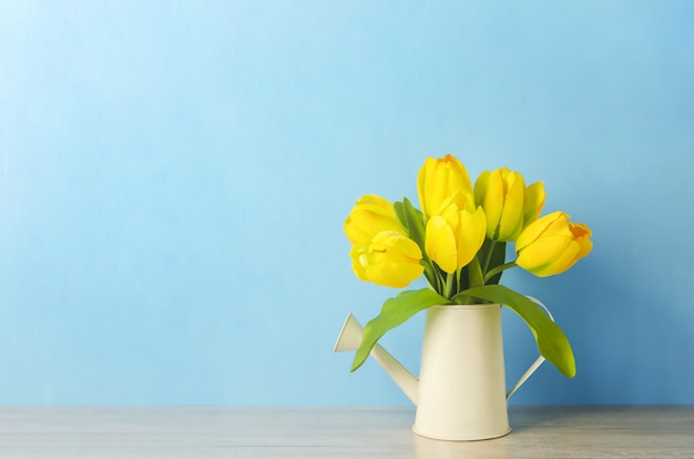 Fleurs de tulipes jaunes artificielles à l'arrosoir