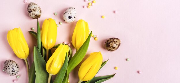 Fleurs de tulipes jaunes et œufs de caille sur une bannière rose pastel.