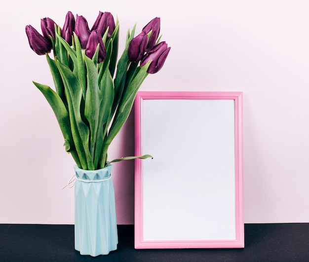 Fleurs de tulipes pourpres fraîches dans un vase avec cadre photo bordure rose