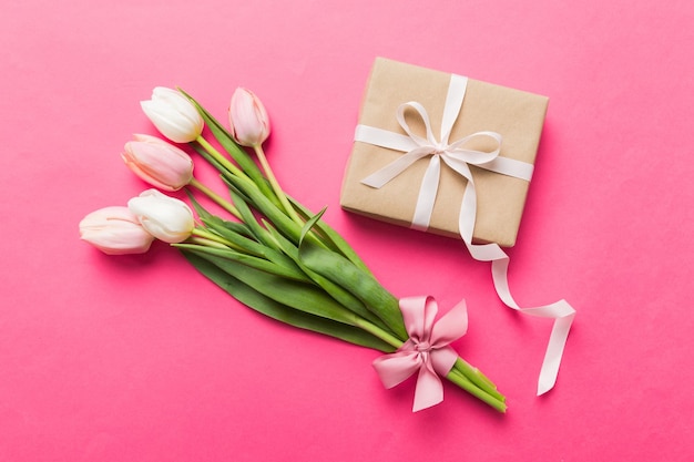 Fleurs de tulipes roses et boîte cadeau ou cadeau sur fond de table coloré Jour de la mère anniversaire Jour de la femme concept de célébration Espace pour le texte vue supérieure