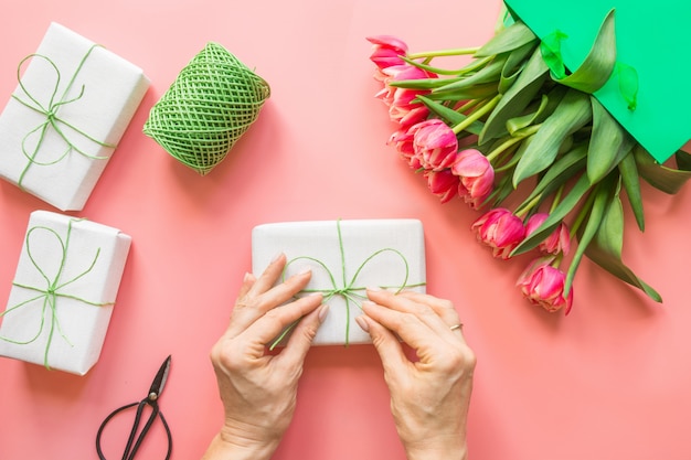 Fleurs de tulipes rouges fraîches dans un sac en papier vert sur rose.