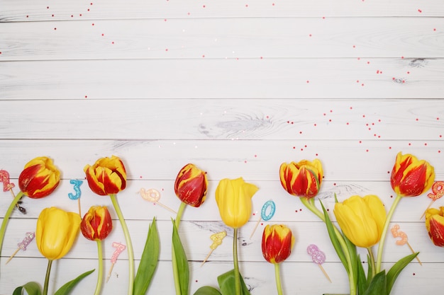 Fleurs De Tulipes Rouges, Jaunes, Bougies Et Confettis Sur Fond En Bois.