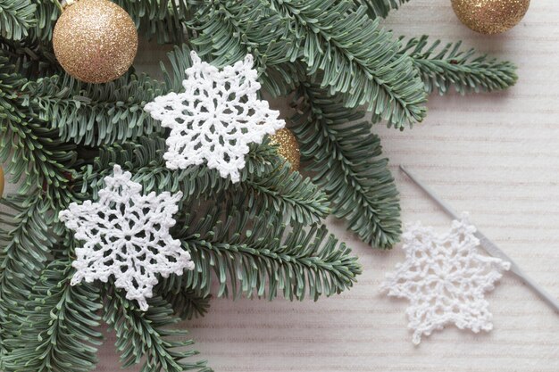 Flocon de neige au crochet blanc de Noël en coton fait à la main en gros plan et vue de dessus des branches de sapin