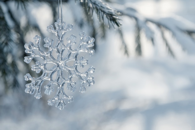 Flocon de verre suspendu à une branche d'épinette enneigée