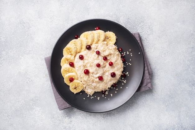 Flocons d'avoine avec du lait avec des canneberges de banane et des graines de sésame. Concept de petit déjeuner sain. Espace copie