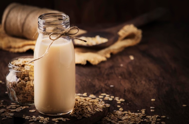 Flocons d'avoine végétaliens lait lait alternatif non laitier dans un espace de copie de table rustique en bois de verre