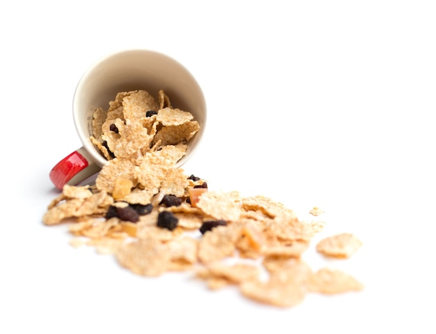 Flocons de céréales à grains entiers qui mélangent des petits fruits et des raisins secs pour le petit déjeuner isolés sur fond blanc