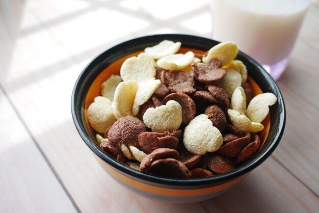 flocons de maïs au chocolat dans un bol et un verre de lait sur la table