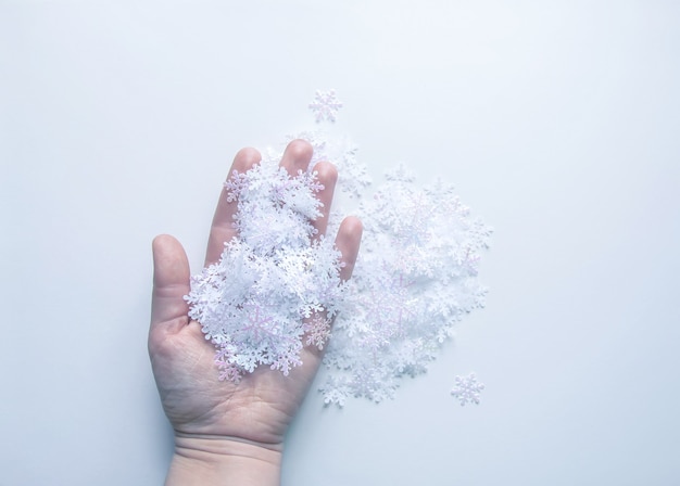 Flocons de neige artificiels blancs à la main sur fond de lumière douce. Fond d'hiver. Modèle décoratif pour cartes, bannière, affiche.