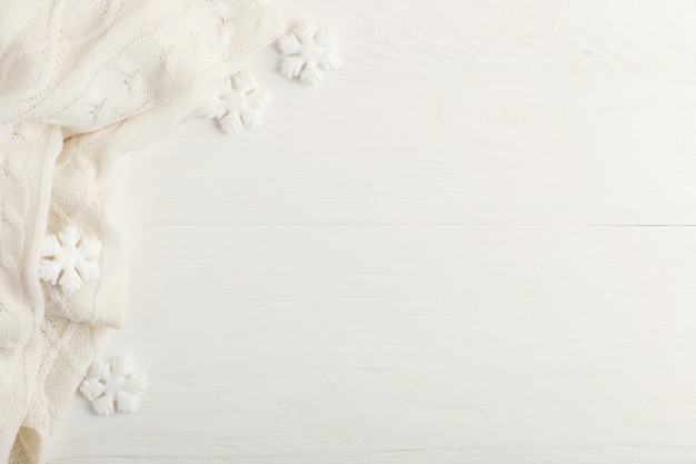 Flocons de neige blancs et écharpe tricotée sur une table en bois