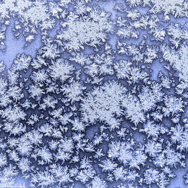 Photo flocons de neige et givre sur la fenêtre gelée en hiver