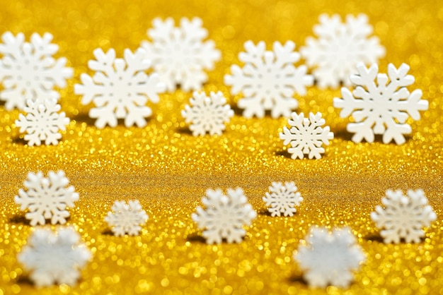 Flocons de neige avec des paillettes scintillantes sur un bokeh doré, copiez l'espace pour le texte.