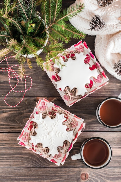 Flocons De Neige En Pain D'épice Avec Glaçage Dans Des Boîtes Ouvertes Et Deux Tasses De Thé Sur Une Table En Bois. Gâterie De Noël. Vue De Dessus Et Verticale