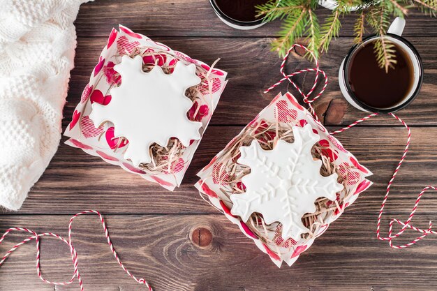 Flocons de neige en pain d'épice avec glaçage dans des boîtes ouvertes et deux tasses de thé sur une table en bois. Gâterie de Noël. Vue de dessus