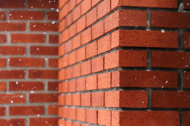 Flocons de neige tombant devant le mur de briques