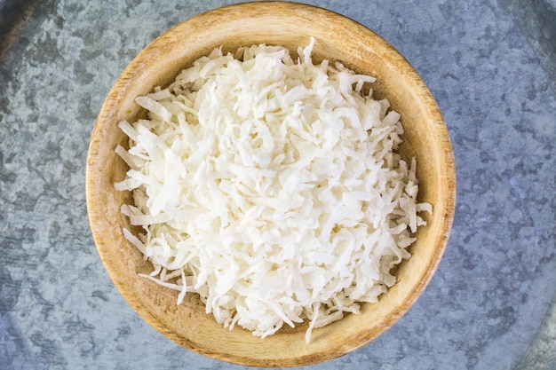 Flocons de noix de coco déshydratés dans un bol en bois.