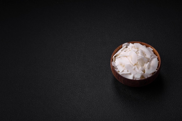 Flocons de noix de coco secs blancs dans un bol en bois préparés pour faire des desserts