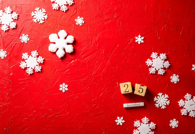 flocons de papier et calendrier en bois sur fond rouge